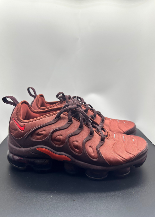Pair of red and brown sneakers on a reflective surface with a light gray background