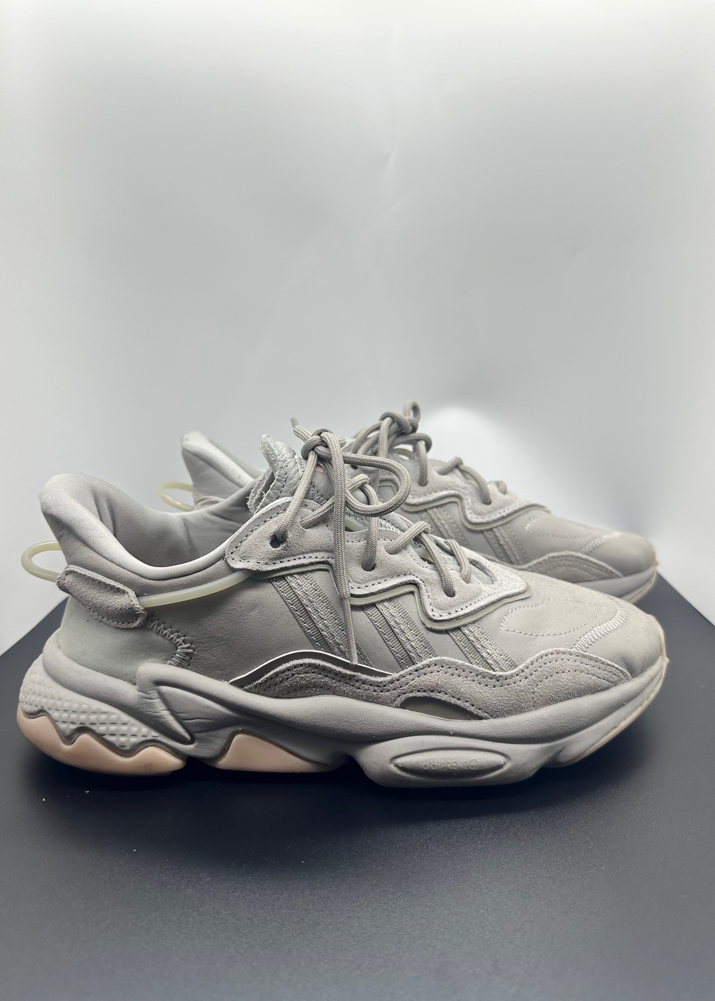 Pair of light gray sneakers on a reflective surface with a gray background